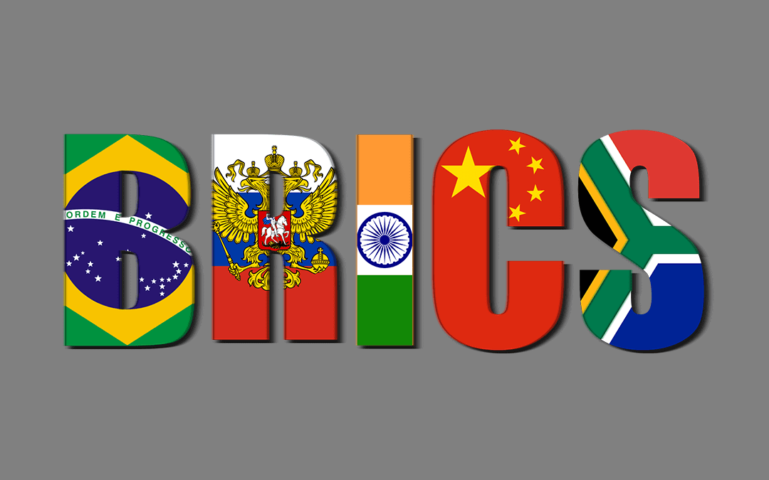The word “BRICS” is spelled in large bold letters, each filled with the flag of a member country: Brazil, Russia, India, China, and South Africa, from left to right, on a plain gray background.