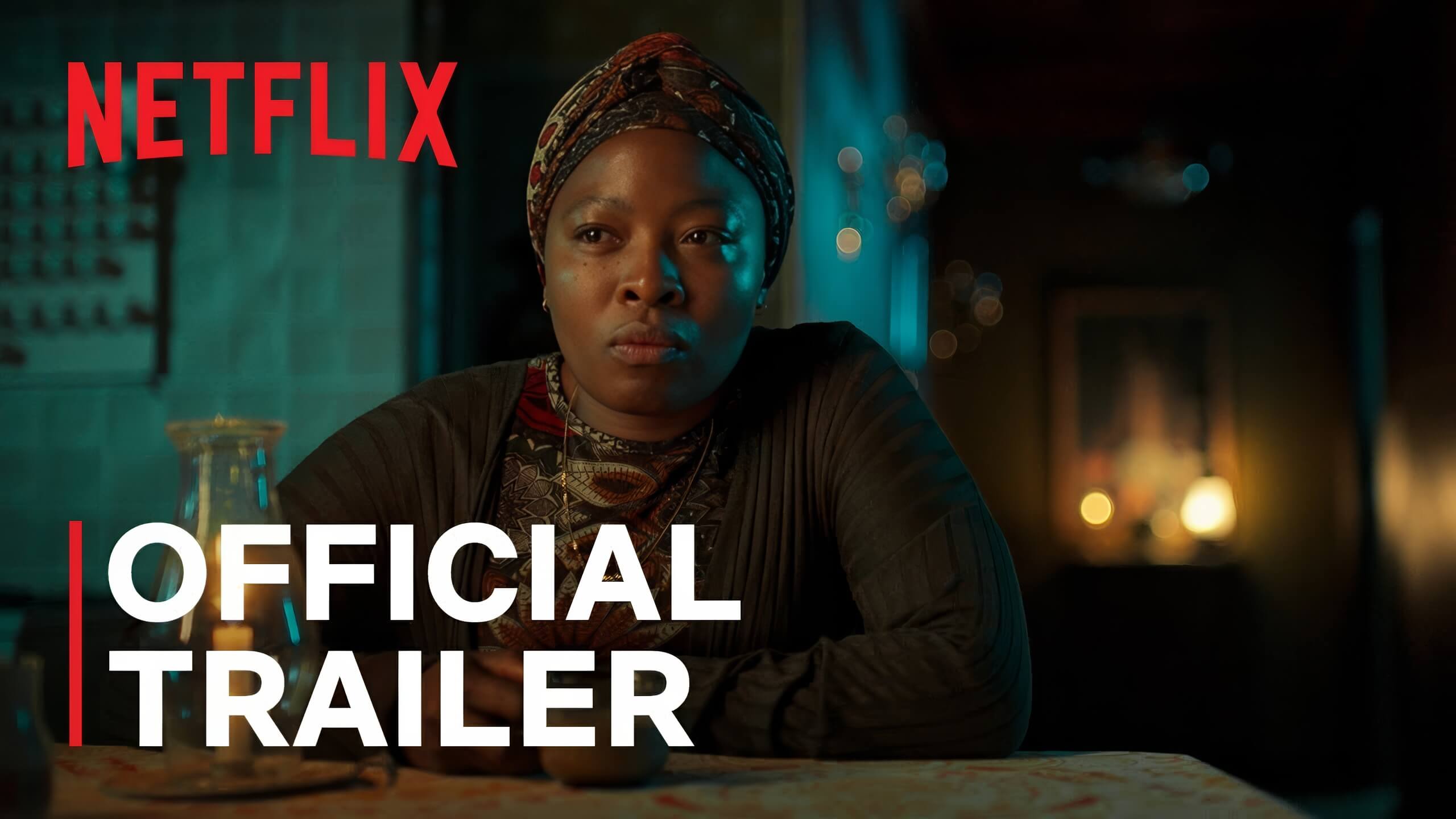 A woman in a patterned headscarf and dark clothing sits at a dimly lit table, looking serious. The red Netflix logo and bold white text reading “Official Trailer” appear on the image. Warm lights and a blurred background suggest an intimate indoor setting.