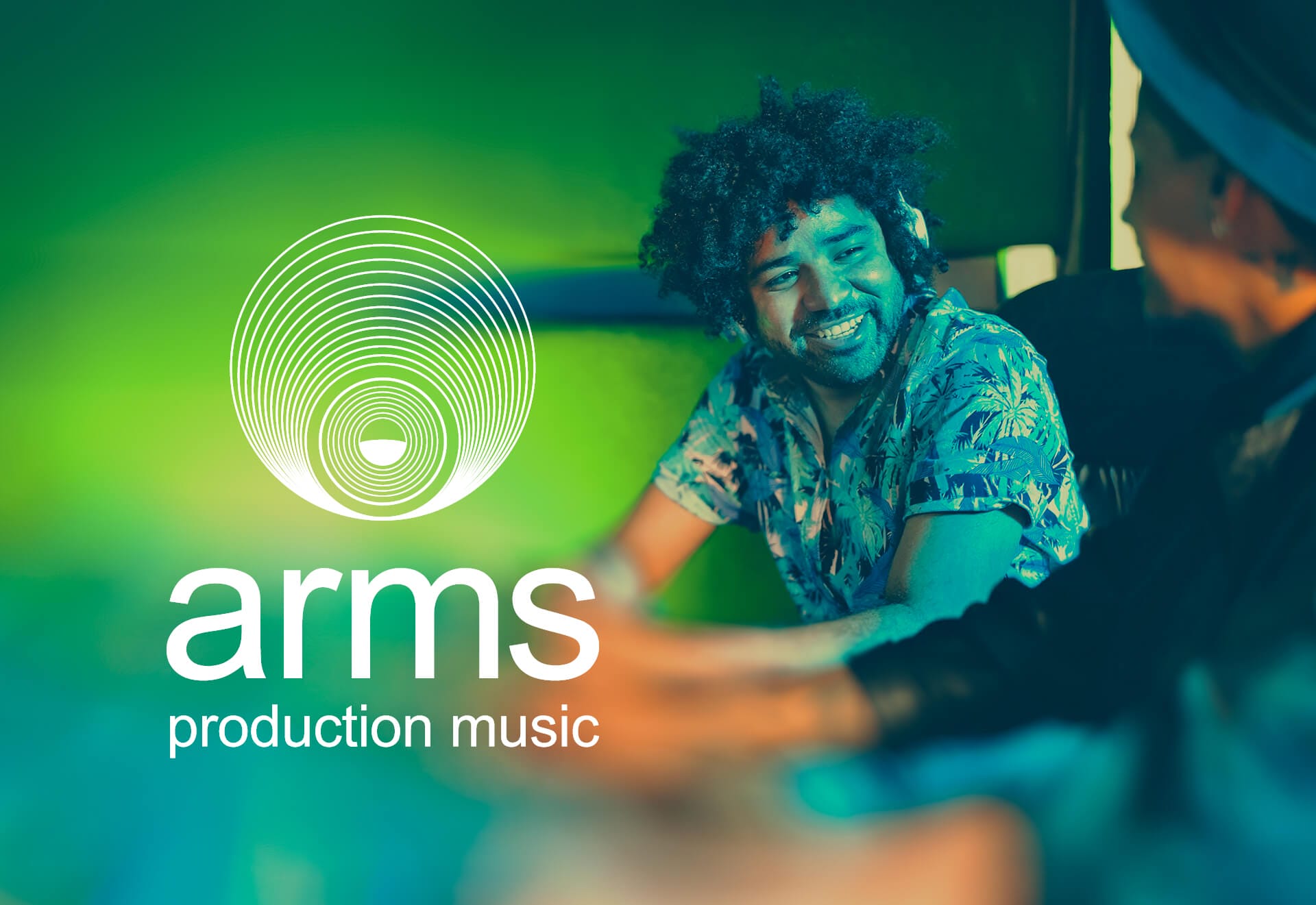 Two people sit and smile at each other in a music studio with green lighting. The left side features a white circular logo and the text “Arms Production Music,” reflecting a creative, friendly atmosphere rooted in music publishing excellence.