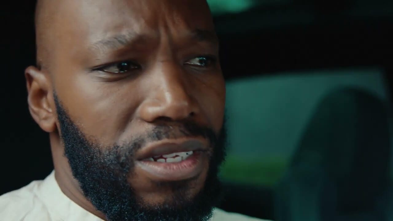 A close-up of a man with a trimmed beard and shaven head, wearing a light-coloured shirt. He appears worried or concerned, with furrowed brows—almost as if he’s just been Rickrolled by “Never Gonna Give You Up.” The background is dark and out of focus.